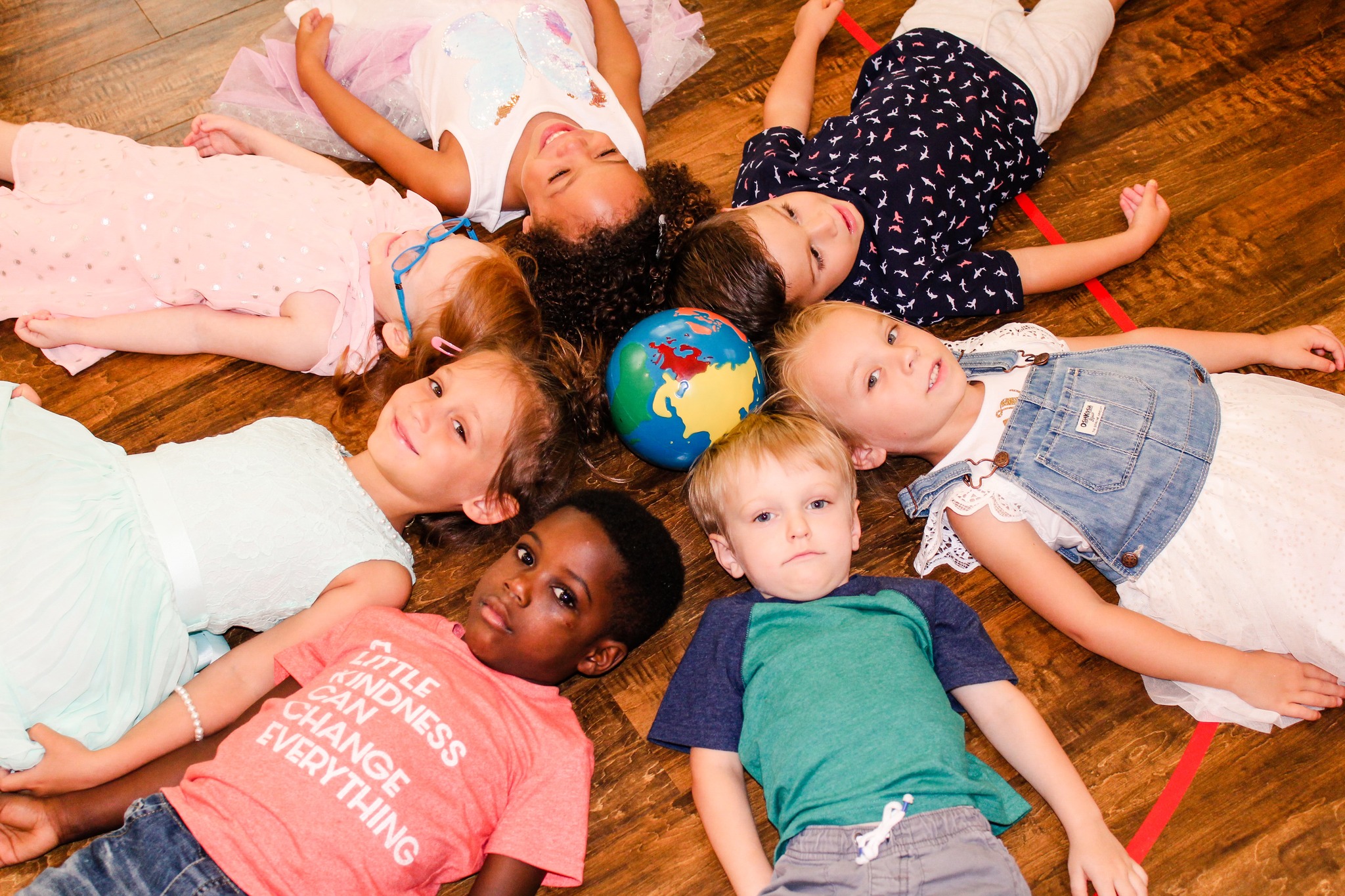 Children lying in a circle around a globe